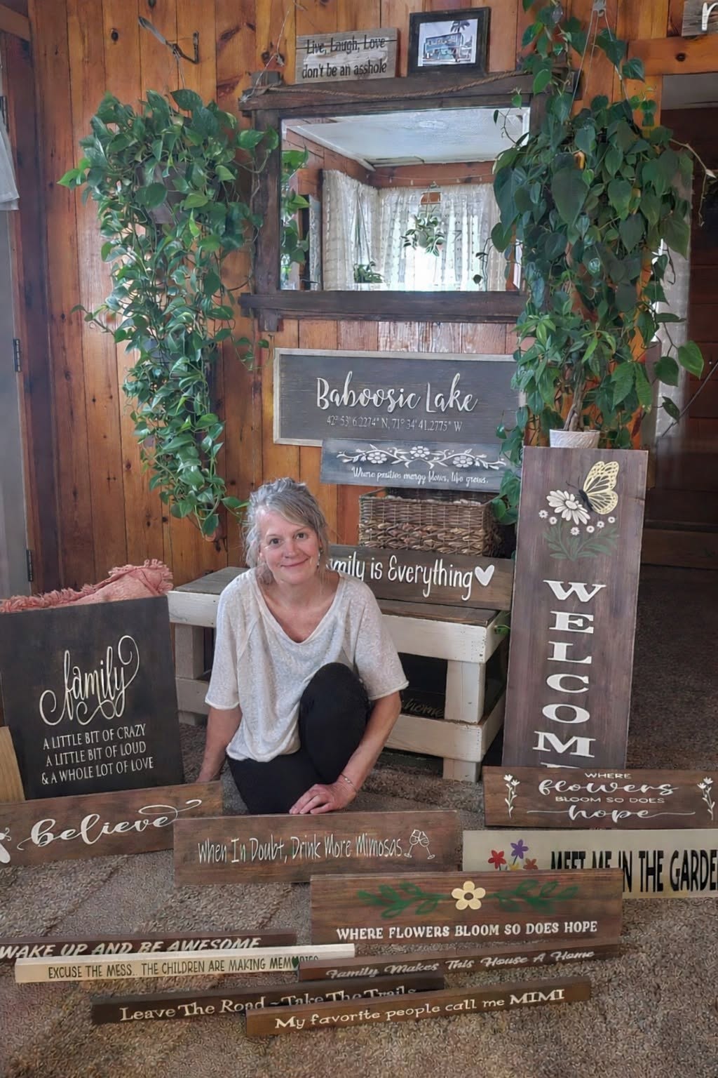 Karen, founder of Lakeside Wood Signs, surrounded by her handcrafted signs