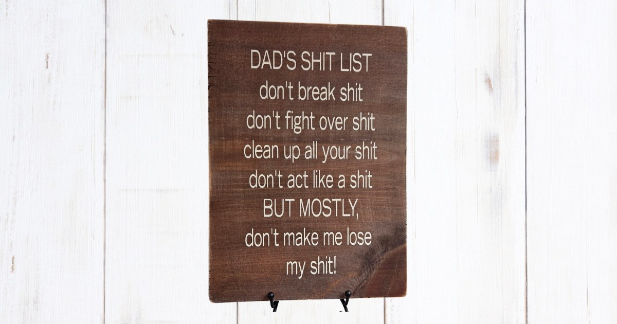 Dad's Shit List sign on dark brown pine