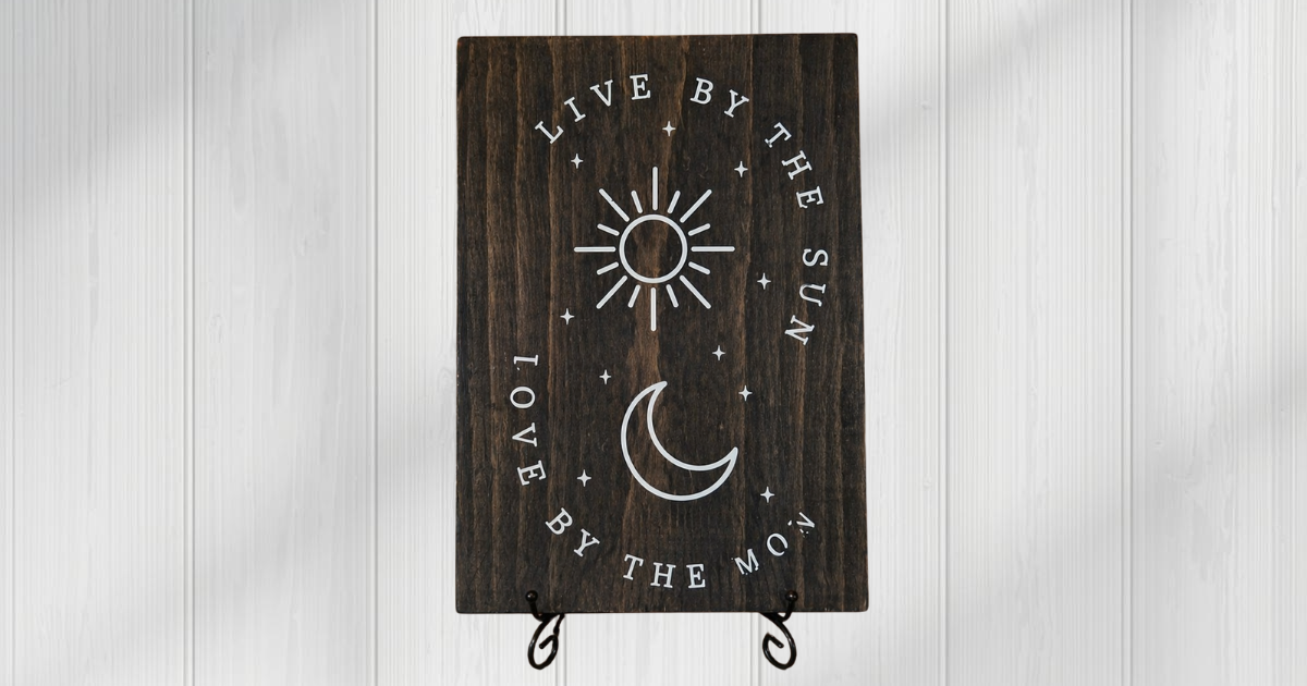 Live by the Sun Love by the Moon sign on dark stained pine